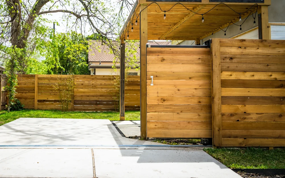 Horizontal cedar privacy fence and sliding gate beside a finished residential patio and lawn